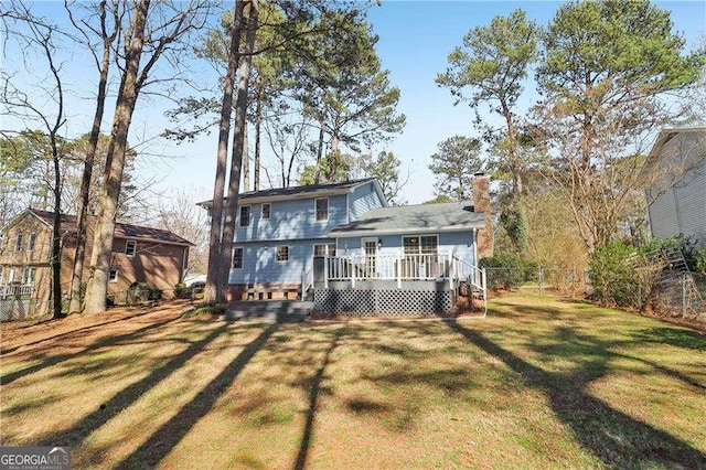 back of house featuring a yard, a chimney, fence, and a wooden deck