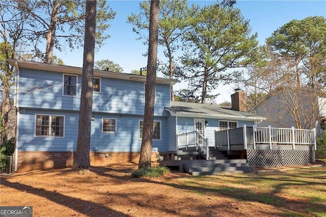 back of property with a chimney, crawl space, a lawn, and a deck