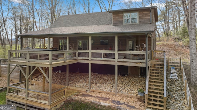 rear view of house with roof with shingles, a deck, and stairs