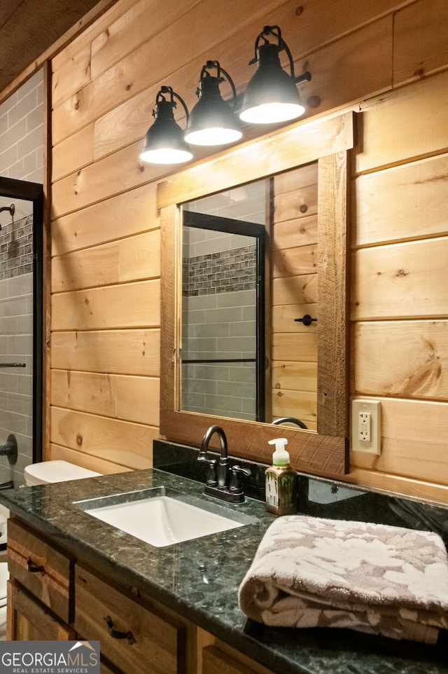 bathroom with a tile shower, wooden walls, and vanity