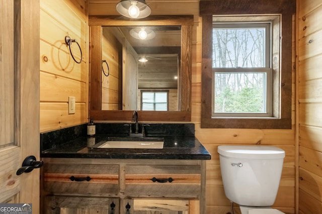 bathroom with vanity, toilet, and wooden walls