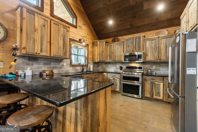 kitchen with decorative backsplash, appliances with stainless steel finishes, a peninsula, vaulted ceiling, and a sink