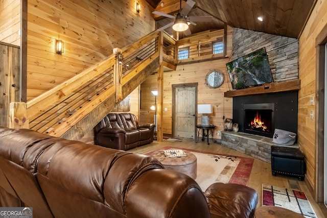 living room featuring a fireplace, a ceiling fan, wooden walls, wood finished floors, and wooden ceiling