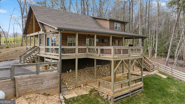 view of front of home featuring roof with shingles, a deck, and stairs