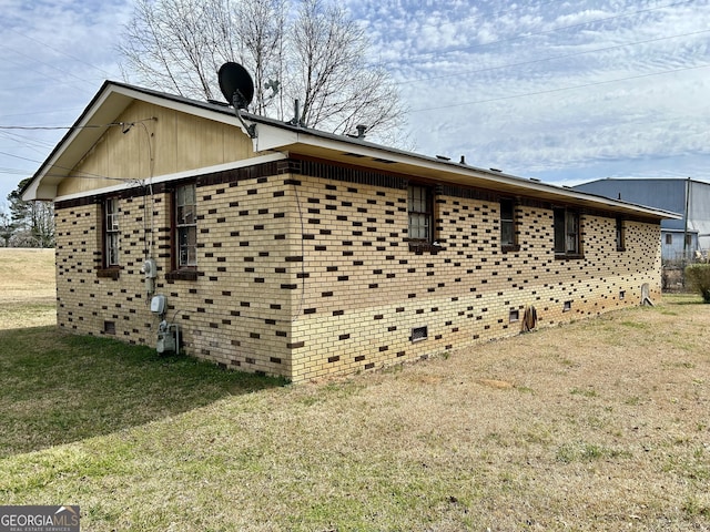 view of property exterior featuring crawl space, brick siding, and a yard