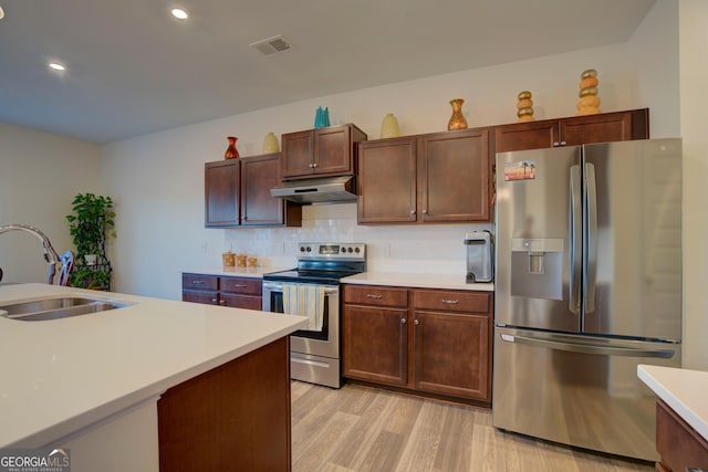 kitchen featuring visible vents, appliances with stainless steel finishes, light countertops, under cabinet range hood, and a sink