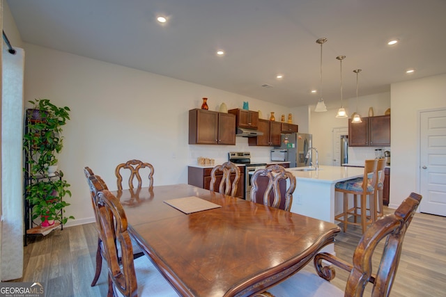 dining area with baseboards, light wood-style flooring, and recessed lighting