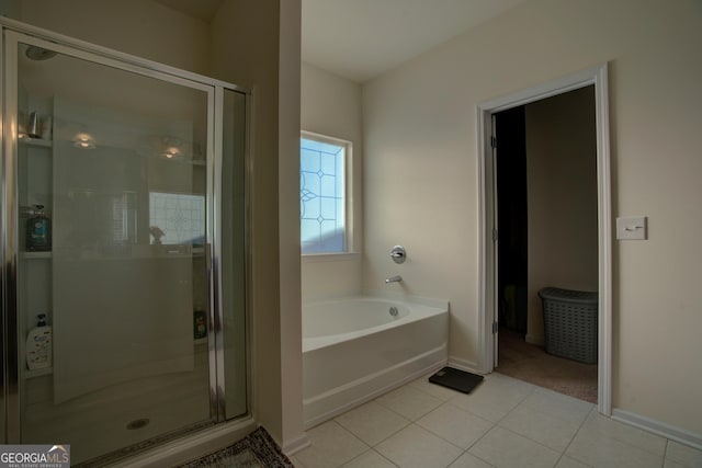 bathroom featuring a stall shower, tile patterned flooring, a garden tub, and baseboards