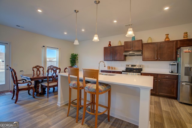 kitchen with under cabinet range hood, a sink, visible vents, light countertops, and appliances with stainless steel finishes