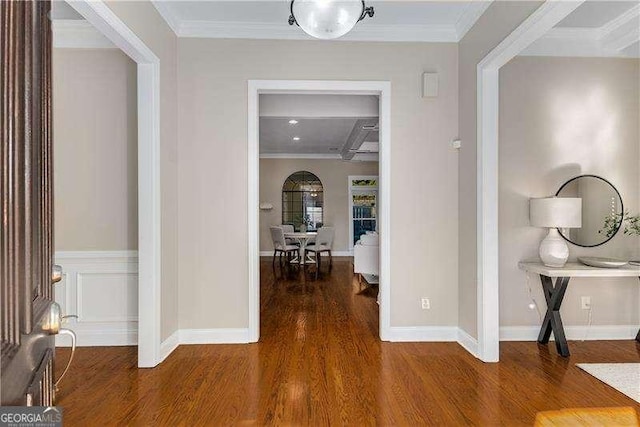 hall featuring crown molding, baseboards, and wood finished floors