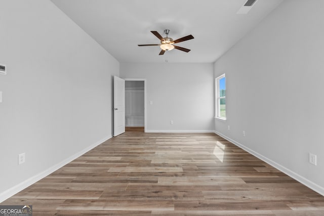 empty room featuring ceiling fan, wood finished floors, visible vents, and baseboards