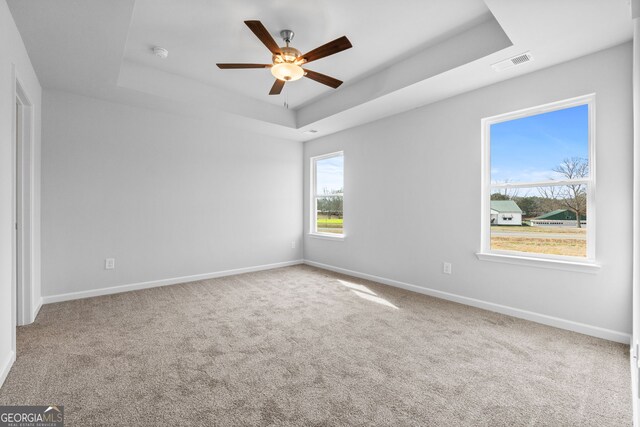 unfurnished bedroom with carpet, a raised ceiling, visible vents, and baseboards