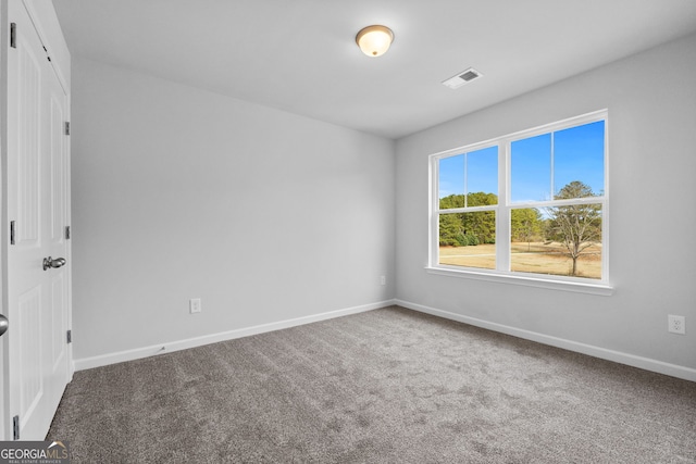 carpeted empty room featuring baseboards and visible vents