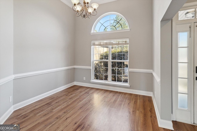 interior space featuring baseboards, a chandelier, and wood finished floors