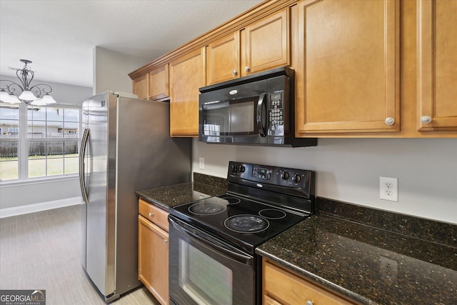 kitchen featuring a chandelier, black appliances, dark stone counters, and baseboards