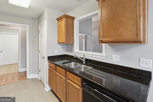 kitchen featuring a sink, baseboards, black dishwasher, brown cabinetry, and dark stone countertops