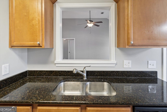 kitchen featuring ceiling fan, dark stone countertops, a sink, and visible vents