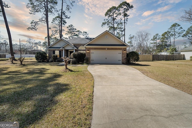 craftsman-style house featuring a garage, brick siding, fence, a yard, and driveway