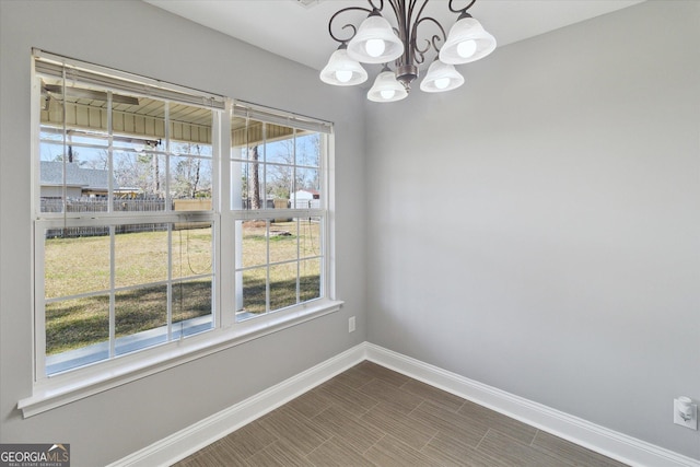 unfurnished dining area with baseboards, a chandelier, and a wealth of natural light