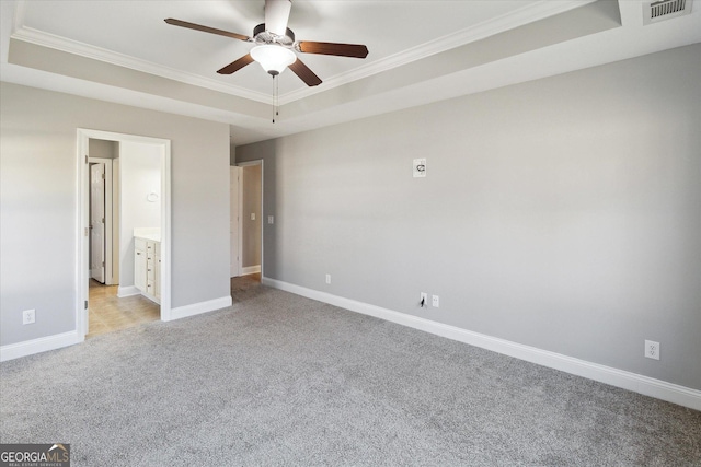 unfurnished bedroom with a tray ceiling, visible vents, ornamental molding, light carpet, and baseboards