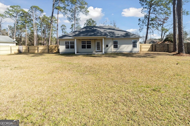 rear view of house with a fenced backyard and a lawn