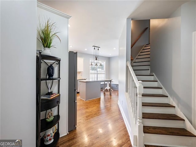 staircase featuring baseboards, wood finished floors, and recessed lighting