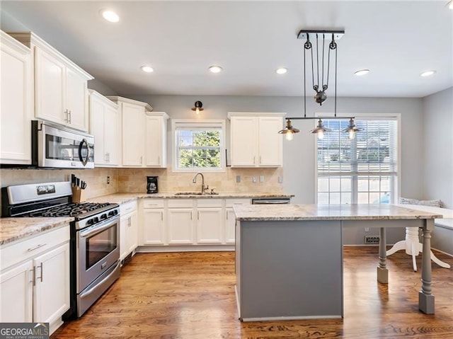 kitchen featuring white cabinetry, appliances with stainless steel finishes, backsplash, and a sink