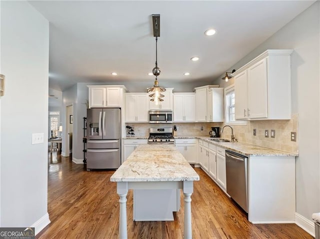 kitchen with appliances with stainless steel finishes, white cabinets, a sink, and backsplash