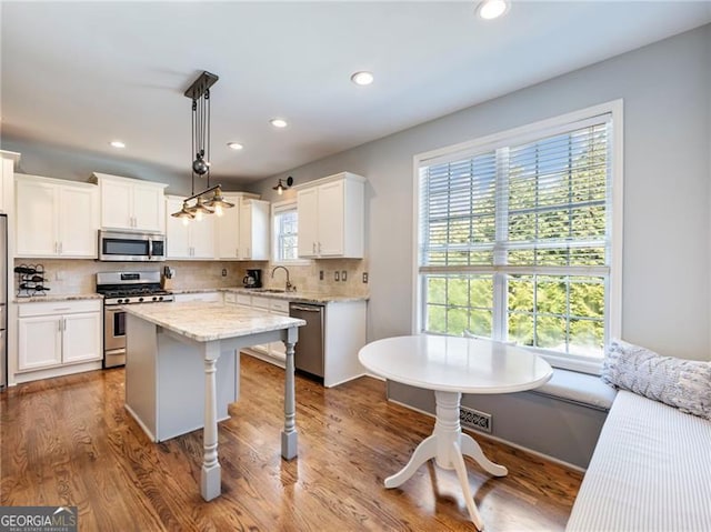 kitchen featuring white cabinets, appliances with stainless steel finishes, decorative backsplash, a center island, and dark wood finished floors