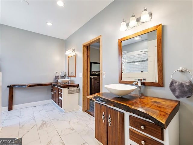 bathroom featuring recessed lighting, two vanities, a sink, baseboards, and marble finish floor