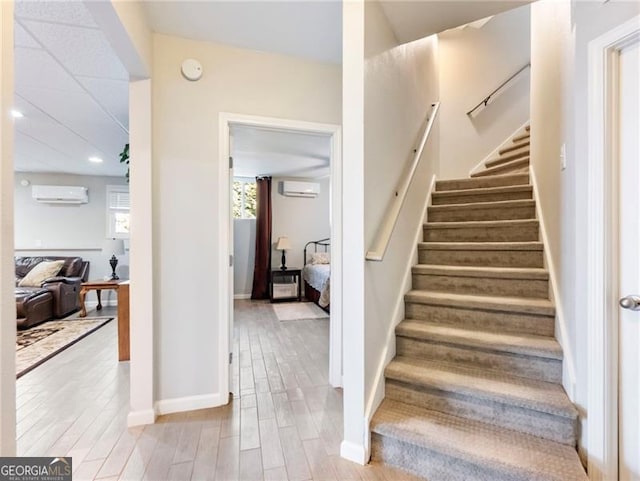 stairway featuring a wall mounted air conditioner, baseboards, and wood finished floors