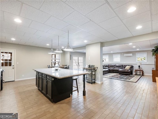 kitchen with light wood-style floors, an AC wall unit, dark cabinetry, and a kitchen breakfast bar