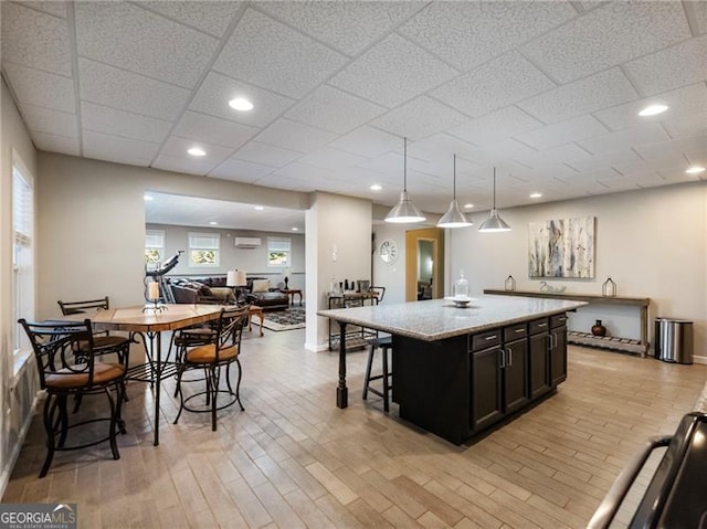 kitchen featuring light wood finished floors, a kitchen island, a breakfast bar area, open floor plan, and a wall mounted AC