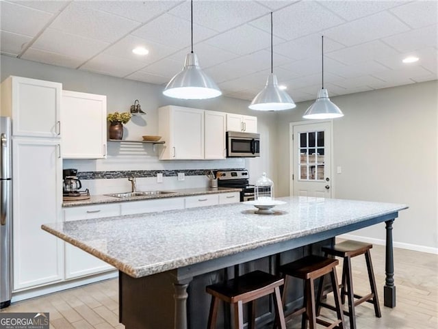 kitchen featuring white cabinets, decorative backsplash, stainless steel appliances, and a sink