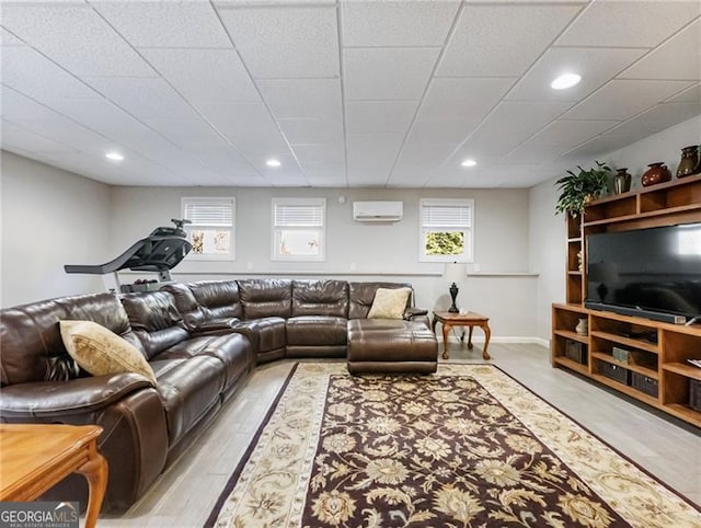 living room featuring recessed lighting, an AC wall unit, baseboards, and wood finished floors