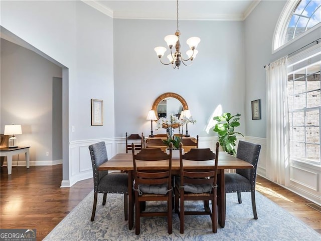 dining space with a chandelier, crown molding, and wood finished floors