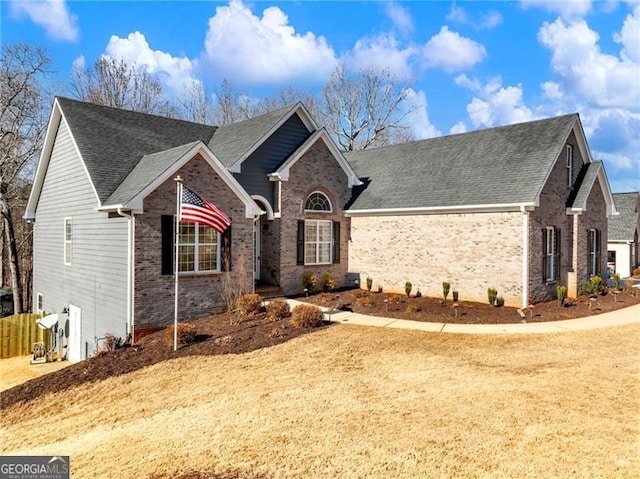 ranch-style house with roof with shingles, fence, and brick siding