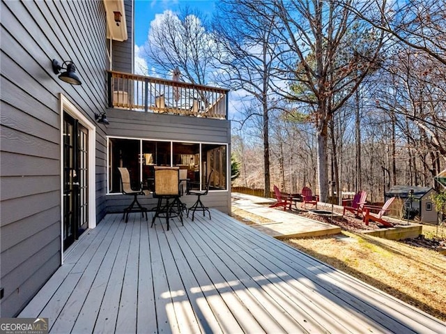 wooden deck featuring outdoor dining area and a fire pit