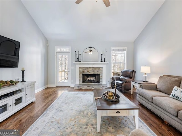 living room featuring high vaulted ceiling, a fireplace, baseboards, and wood finished floors