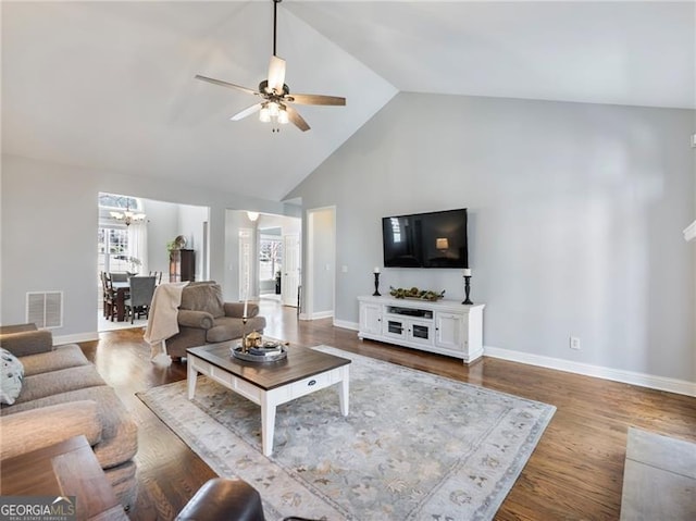 living area with ceiling fan with notable chandelier, dark wood finished floors, visible vents, and baseboards