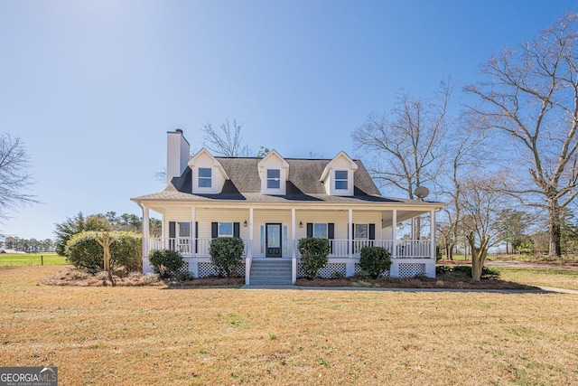 view of front of home featuring covered porch, a chimney, and a front yard