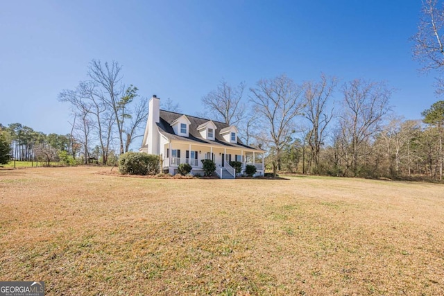 view of front of home featuring covered porch, a chimney, and a front lawn