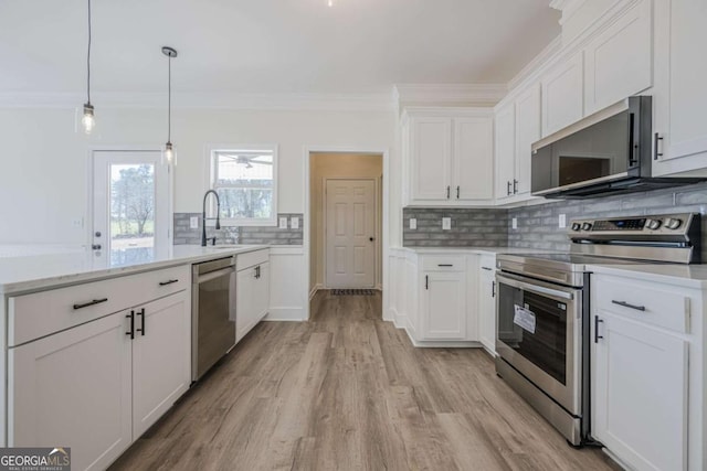 3800 George Williams Rd, Monroe, GA 30656 - kitchen with stainless steel appliances, a peninsula, ornamental molding, light wood-style floors, and white cabinets
