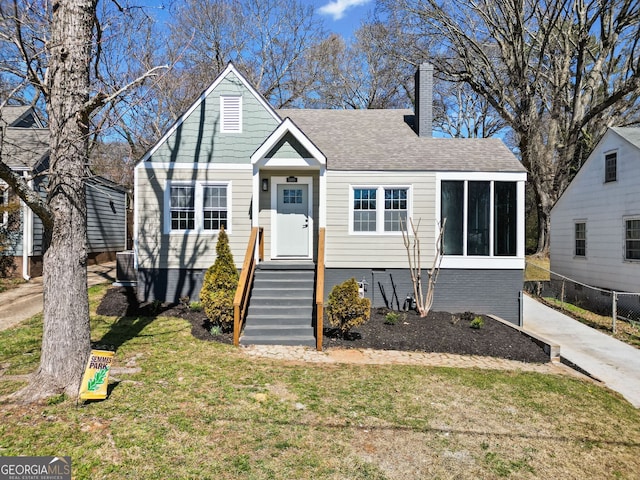 bungalow-style house featuring roof with shingles, a chimney, and a front yard