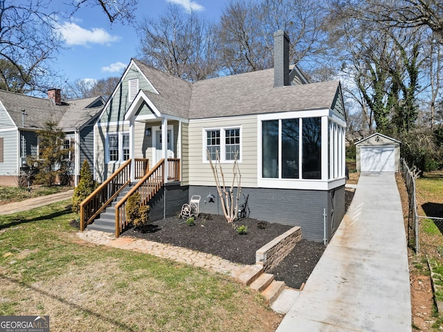 bungalow with roof with shingles, a chimney, a garage, an outdoor structure, and driveway