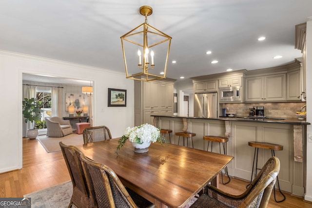 dining room with light wood-type flooring, an inviting chandelier, ornamental molding, and recessed lighting