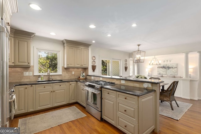 kitchen featuring stainless steel stove, light wood-style floors, open floor plan, a sink, and a peninsula