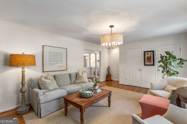 living room featuring crown molding, a notable chandelier, a textured ceiling, and wood finished floors