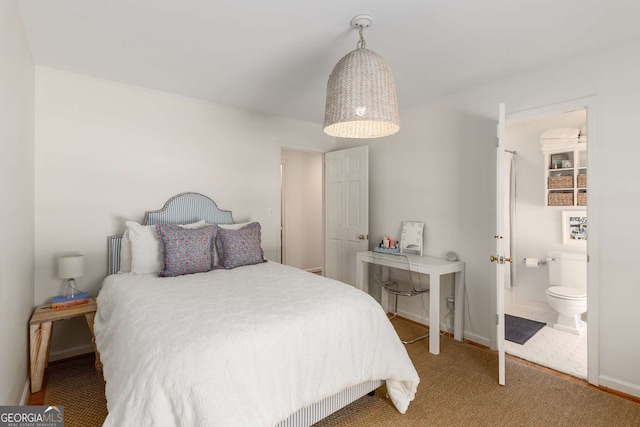 carpeted bedroom with ensuite bathroom and baseboards