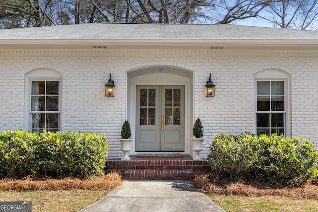 entrance to property with brick siding and roof with shingles